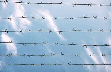 Barbed wire and blue sky with clouds