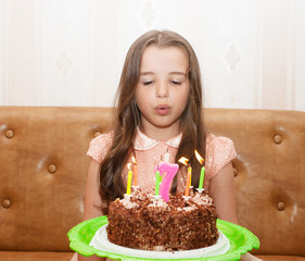 little girl blowing out the candles on a birthday cake
