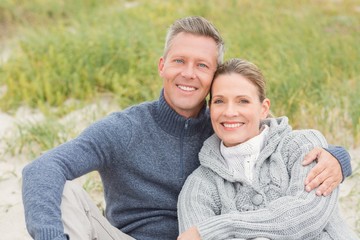 Fototapeta premium Smiling couple sitting on the sand