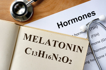 Melatonin  word written on the book and hormones list.