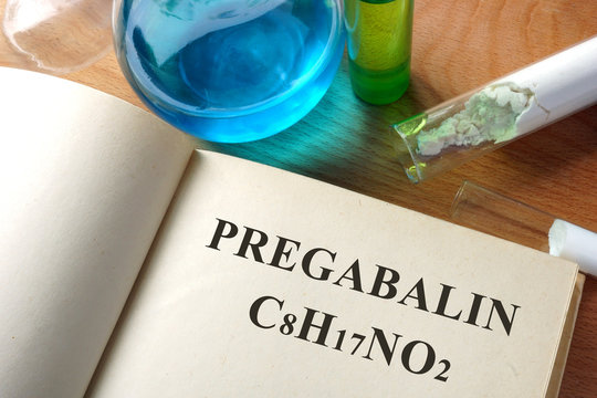 Book with Pregabalin and test tubes on a table.