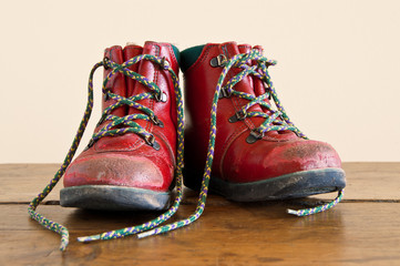 A pair of red worn out children`s boots.