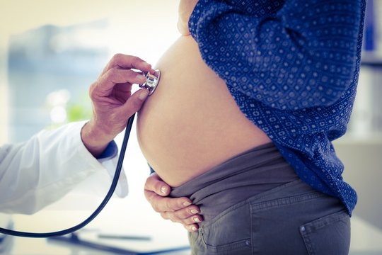 Cropped image of doctor examining pregnant woman in clinic