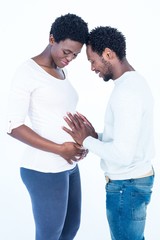 Cheerful man touching his pregnant wife belly while standing 