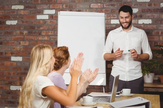 Women praising male colleague during presentation 