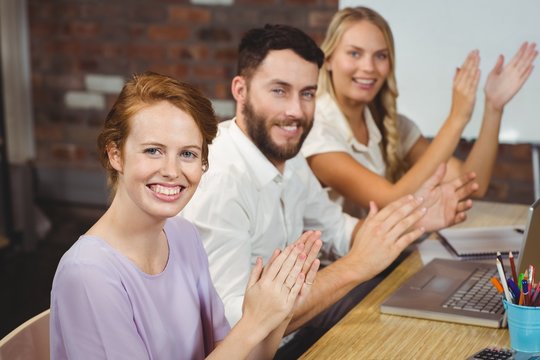 Portrait of happy colleagues clapping at meeting 