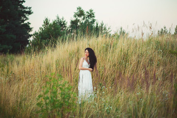 beautiful pregnant woman in a field with a bouquet in hands