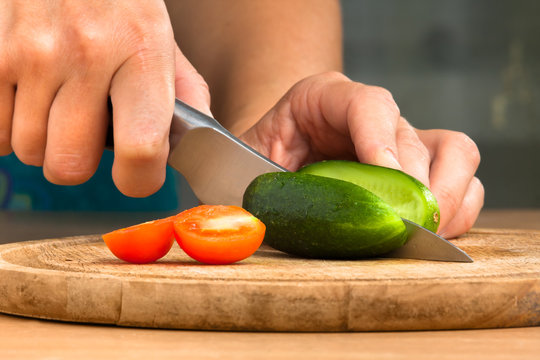hands of woman slicing cucumber on the cutting board