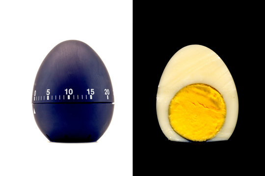 Timer as a black egg isolated on a white background and sliced boiled cooked egg refined with yolk on a black background