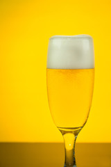 beer in a glass on yellow backlight background, soft focused