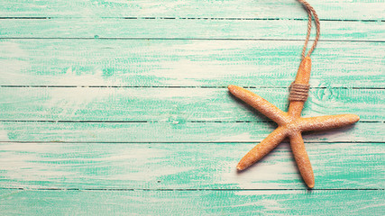 Fototapeta na wymiar Marine item sea star on turquoise wooden background.