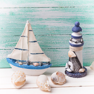 Decorative lighthouse,  sailing boat and marine items on wooden