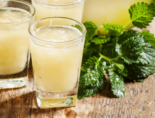 Melon juice in a glass, mint  and slices of melon on a wooden ba