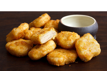 Pile of golden deep-fried battered chicken nuggets with empty ru