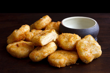 Pile of golden deep-fried battered chicken nuggets with empty ru