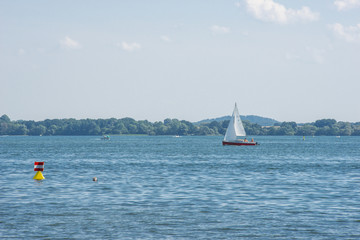 Fototapeta na wymiar Segelboot, Motorboote und Badende, Boje, Schweriner Außensee, Mecklenburg-Vorpommern, Deutschland