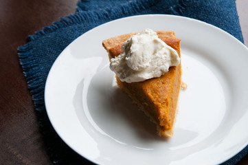 piece of pumpkin pie on a plate with a dollop of whipped cream