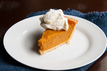 piece of pumpkin pie on a plate with a dollop of whipped cream