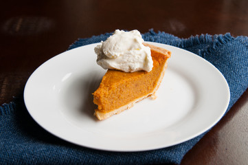 piece of pumpkin pie on a plate with a dollop of whipped cream