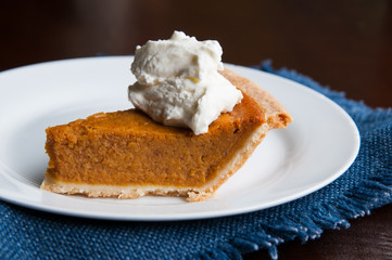 piece of pumpkin pie on a plate with a dollop of whipped cream
