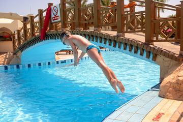 Naklejka premium Little boy diving into a resort swimming pool