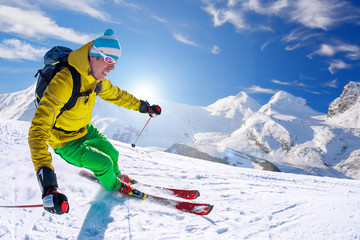 Fototapeta na wymiar Skier skiing downhill in high mountains against blue sky