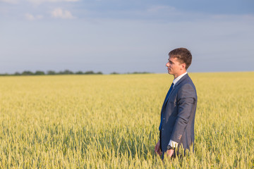 Naklejka na ściany i meble happy farmer, businessman, standing in wheat field with his