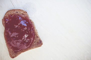 toasted wholemeal crisp bread with jam on a bright wood background