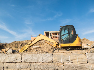 Digger on a construction site building a stone wall
