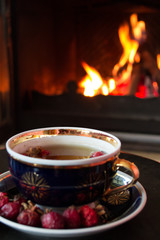 Rosehip tea in front of roaring fire in a fire place
