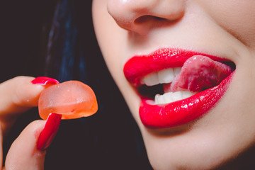 Beautiful woman licking her red lips before tasting jelly sweet