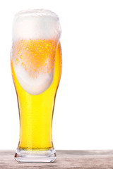 Frosty glass of light beer on a wooden table