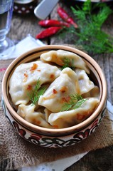 dumplings with potatoes and mushrooms with fried onions in a traditional ceramic plate on a wooden table. ukrainian traditional cuisine. 
