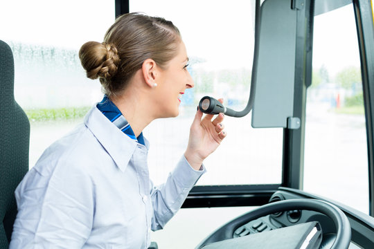 Busfahrererin spricht in Bus Mikrofon und macht eine Durchsage