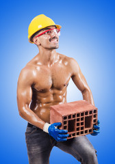 Muscular builder with bricks on white