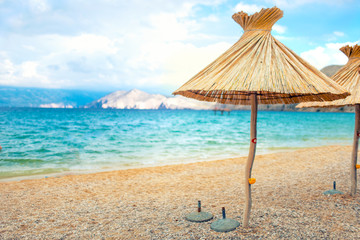 beach straw umbrella lounger chair with sand and clear water. Sea mediteraneean coastline landscape