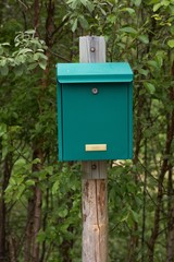 Green mailbox on a wooden post