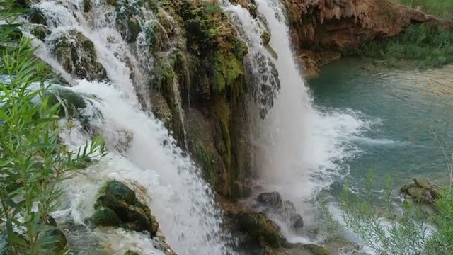 High angle slow motion panning shot of waterfall in rocky landscape / Havasupai, Arizona, United States