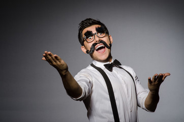 Young caucasian man with false moustache against gray
