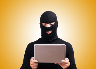 Hacker with computer wearing balaclava