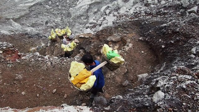 Unidentified workers carrying heavy loads of sulfur inside the crater of Kawah Ijen volcano in East Java, Indonesia.