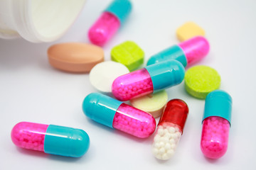 Colored pills, tablets and capsules on white background