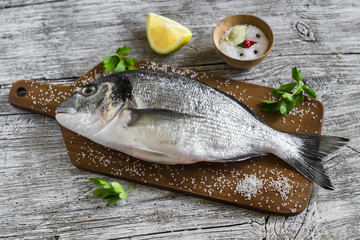 fresh Dorado fish with lemon and spices on a light wooden surface