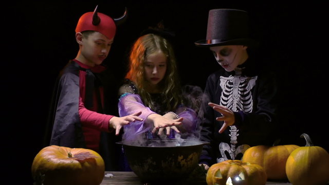 Group of kids in Halloween costumes preparing magic potion  