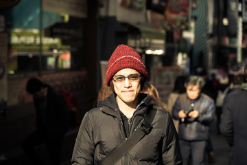 Asian male with winter jacket and red hat stand  in city instagram t