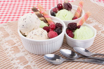 Ice cream with mixed fruits in white bowl with waffle sticks.