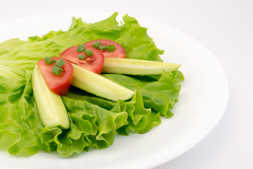 fresh vegetables on a salad leaf in plate on a white background