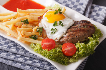 beefsteak with fried egg and fries on a plate closeup. horizontal
