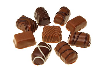 Various tasty chocolates candies on white background, focus is on middle candy
