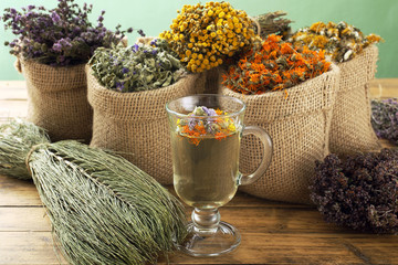 tisana o infuso di piante spontanee in vaso di vetro sfondo rustico